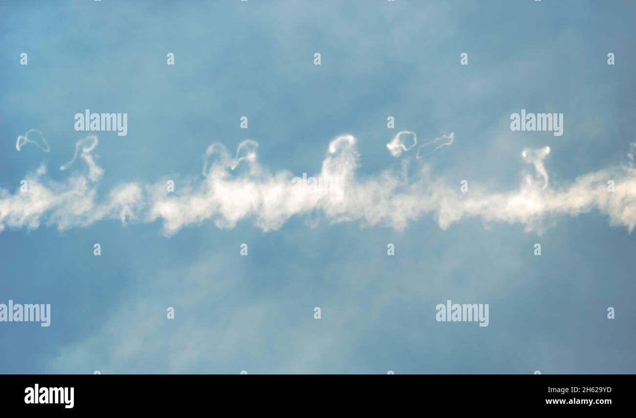 White airplane trace and clouds in a blue sky Stock Photo
