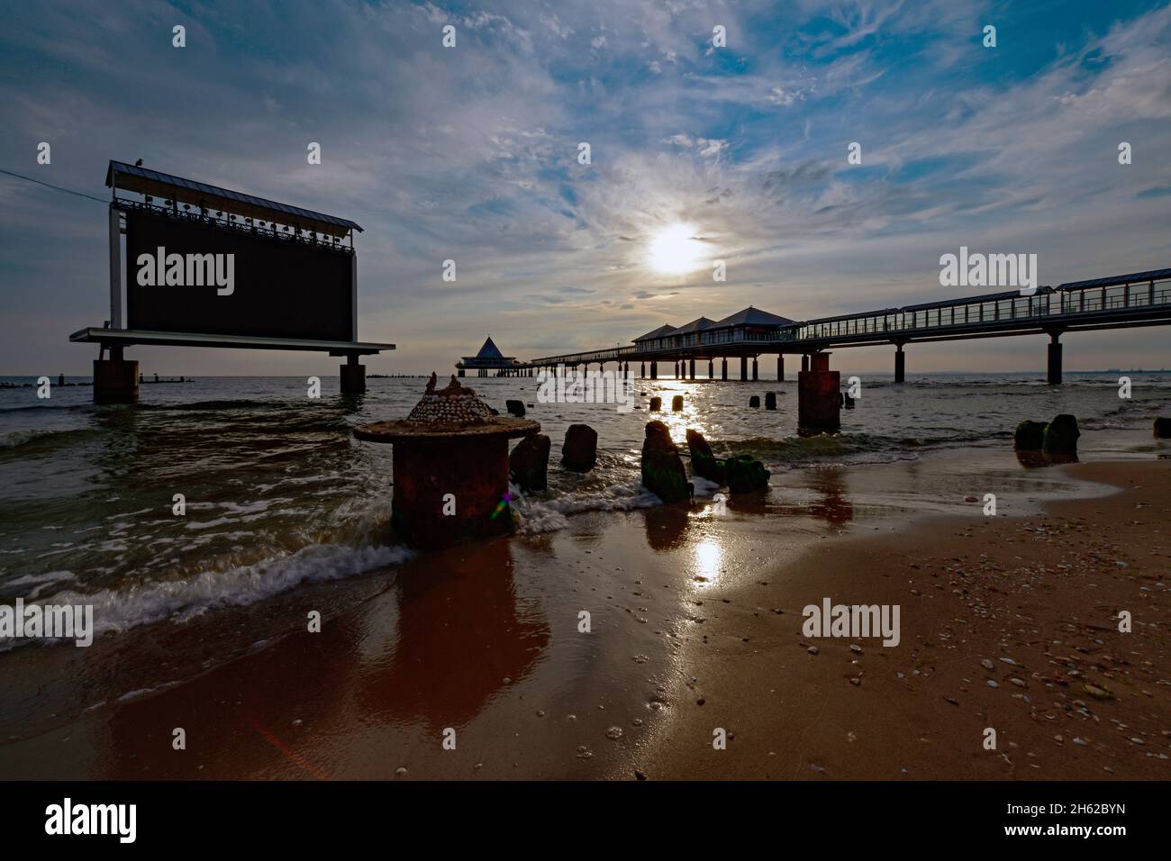 view over the beach with the entire striking pier and projection led wall standing in the water on the beach of heringsdorf at sunrise Stock Photo