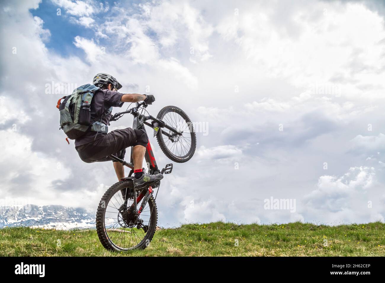 wheelie with e-bike on a green field,one man 37 years old,dolomites,belluno,italy Stock Photo