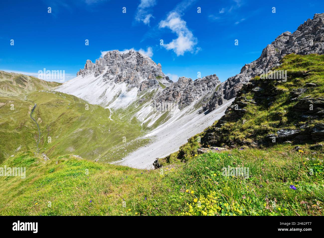 alpine mountain landscape with green grass and wild rock mountains on a ...