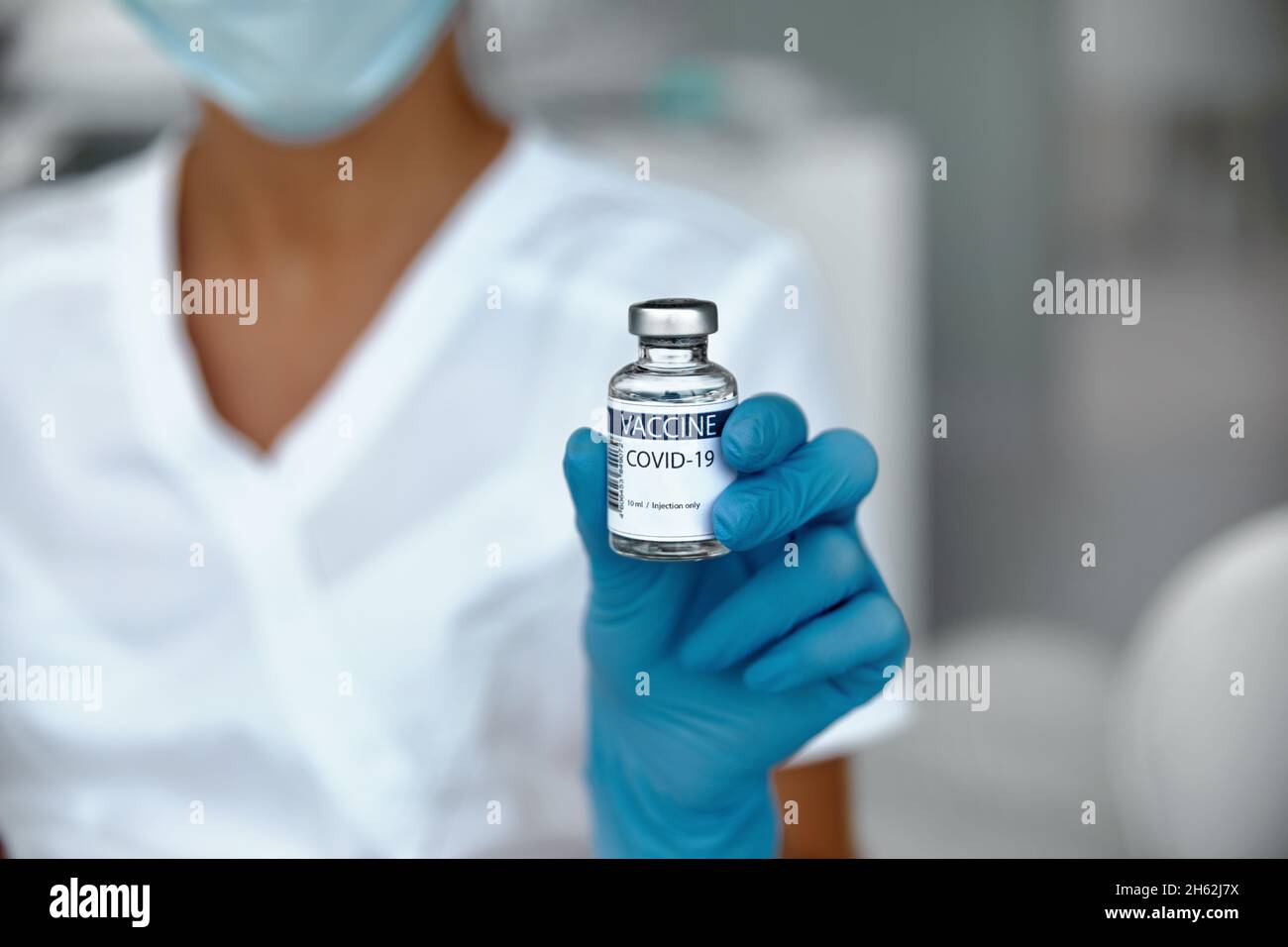 Coronavirus Vaccine in glass bottle in hand of doctor.  Vaccine jar on white background in blue glovs. Vaccine Concept of fight against coronavirus Stock Photo