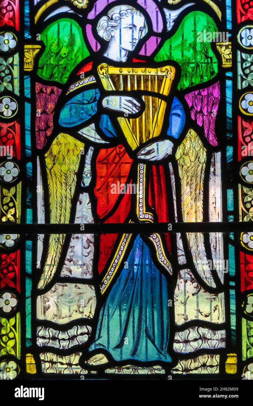 england,hampshire,test valley,king's somborne,the parish church of st.peter and st.paul,stained glass window depicting an angel playing music Stock Photo