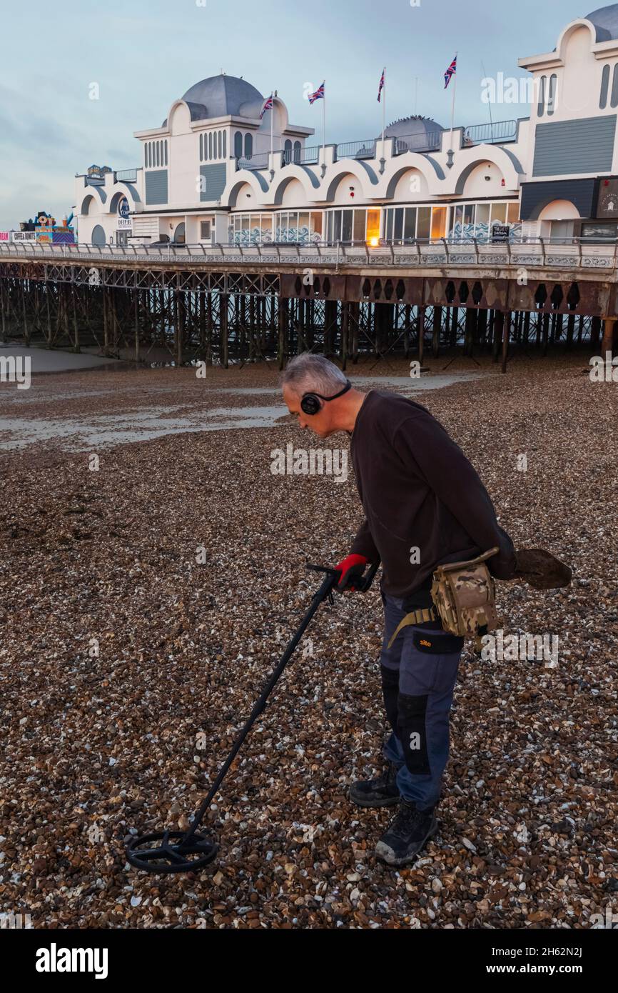 england,hampshire,portsmouth,southsea,man metal detecting on beach and