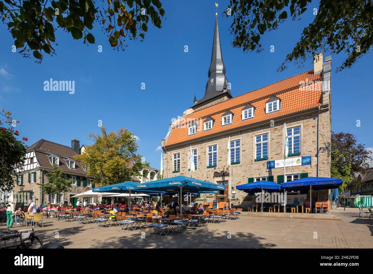 germany,ratingen,bergisches land,rhineland,north rhine-westphalia,market square,people sit in the street restaurant in front of the buergerhaus,formerly town hall,behind the catholic parish church of saint peter and paul Stock Photo