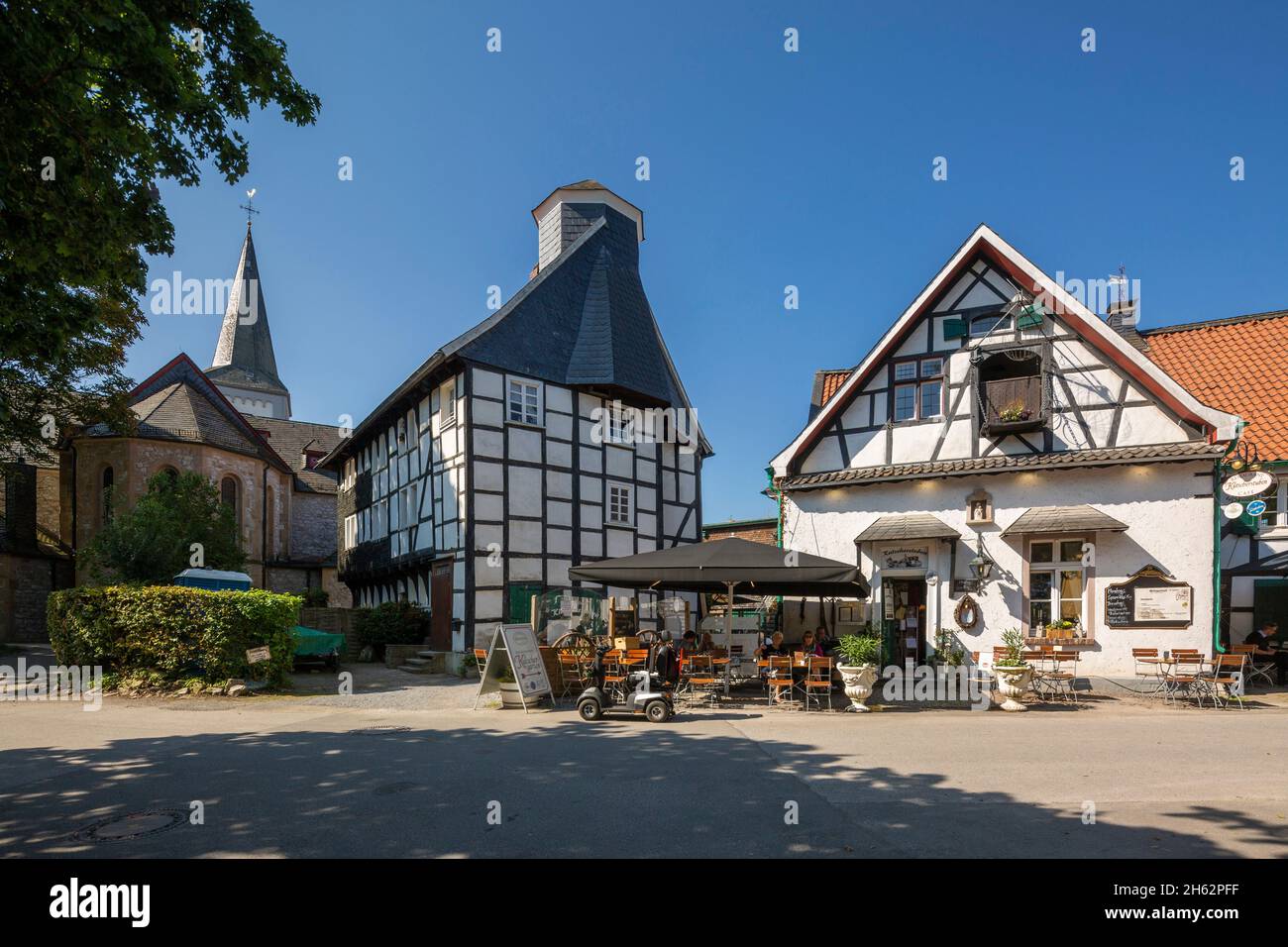 germany,wuelfrath,wuelfrath-duessel,bergisches land,niederbergisches land,niederberg,rhineland,north rhine-westphalia,dorfstrasse in the village of duessel,from left to right catholic church st. maximin,half-timbered house eyser,eyserhaus,residential house,formerly kuesterhaus and school,half-timbered building 'am iser 'with kutscherstuben restaurant and cafe Stock Photo