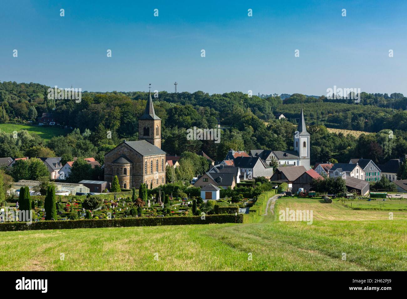germany,wuelfrath,wuelfrath-duessel,bergisches land,niederbergisches land,niederberg,rhineland,north rhine-westphalia,hill landscape with panorama of the village duessel,in front the cemetery,left the protestant church,right the catholic church st. maximin,romanesque,pillar basilica Stock Photo
