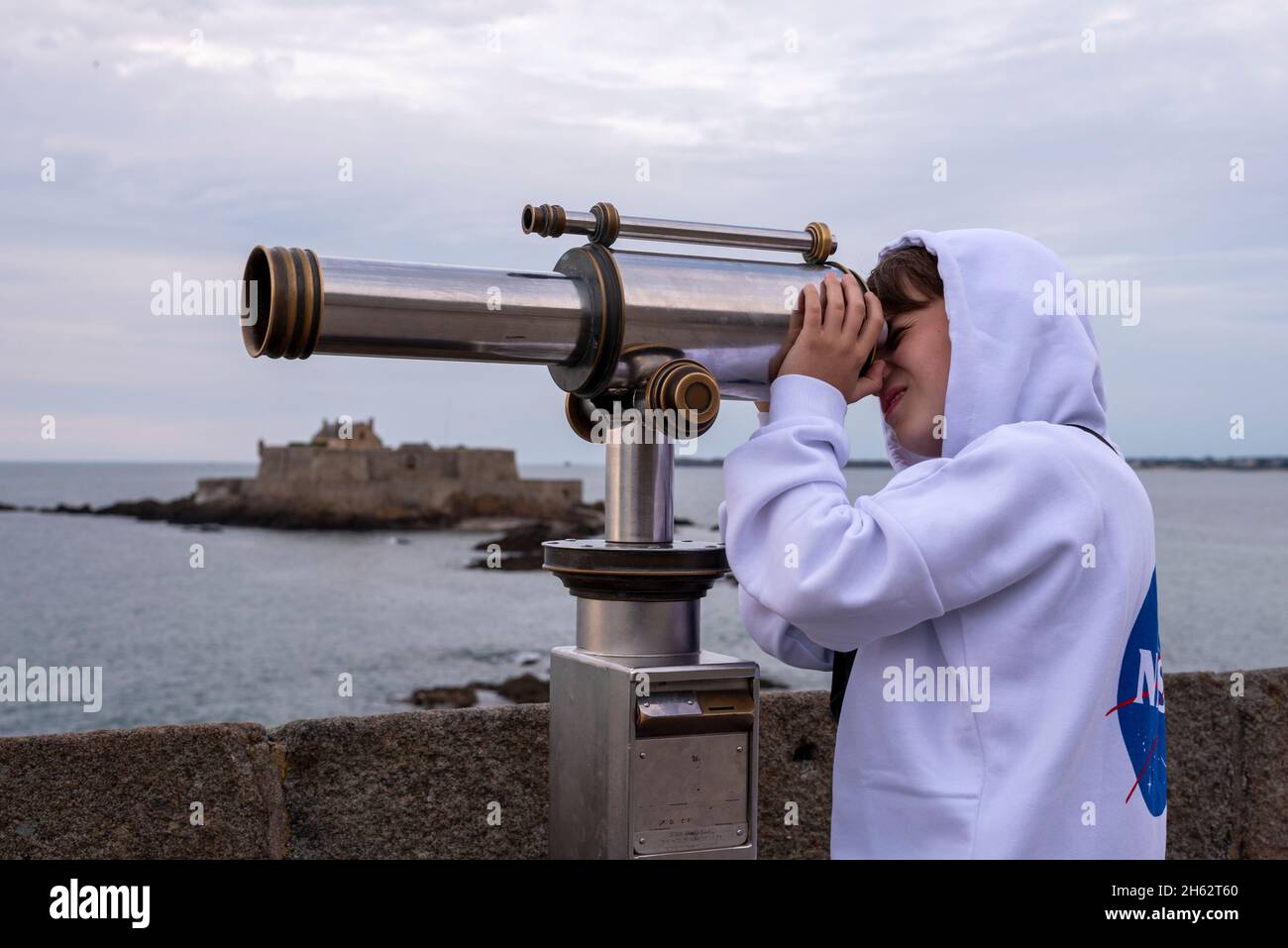 france,brittany,ille et vilaine,saint malo,boy looks through a telescope,tidal island petit-bé with the fort national,atlantic coast Stock Photo