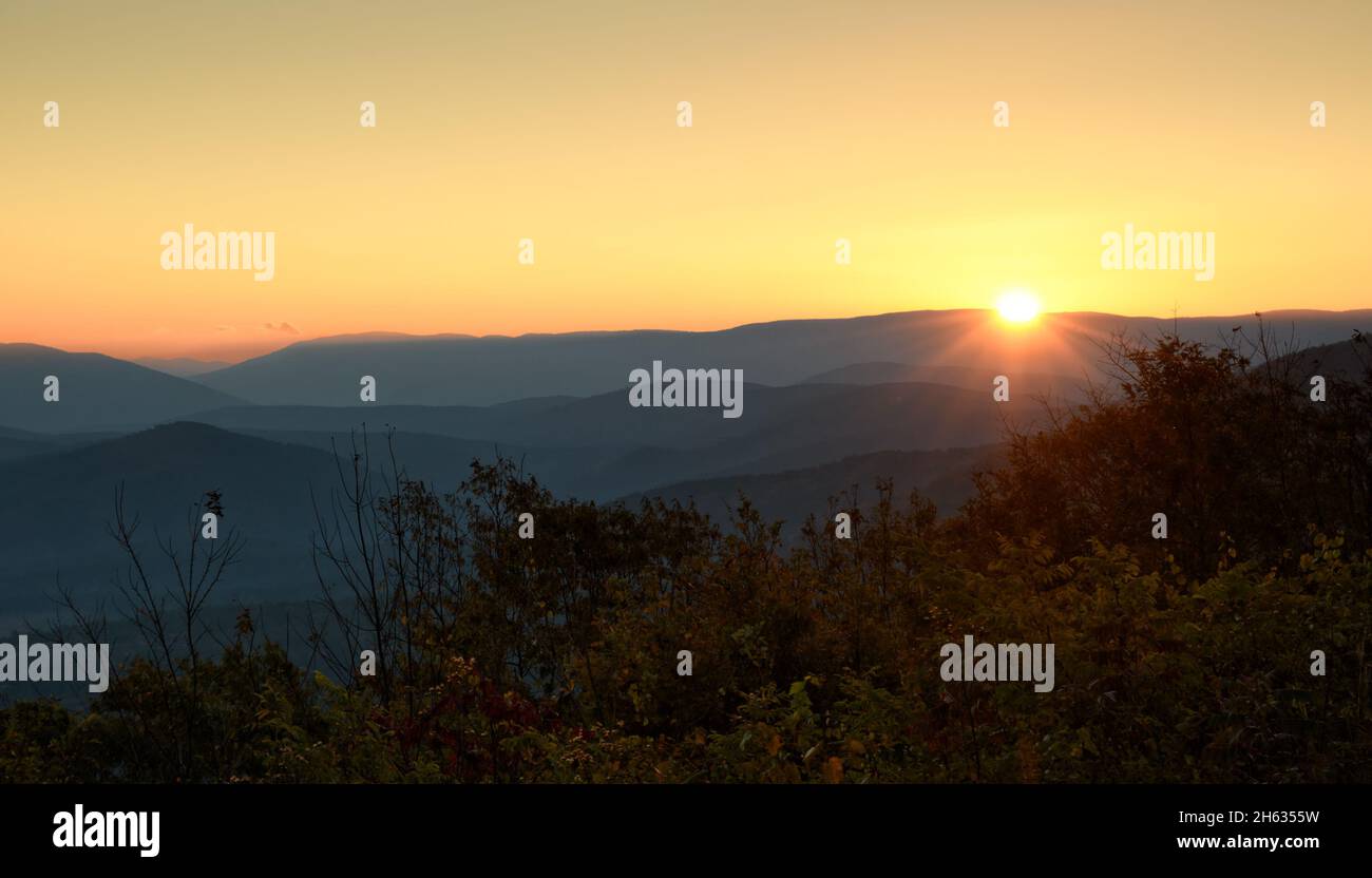 Sunrise with rays spilling over a mountain at Ouachita National forest, with haze over valleys between mountains Stock Photo