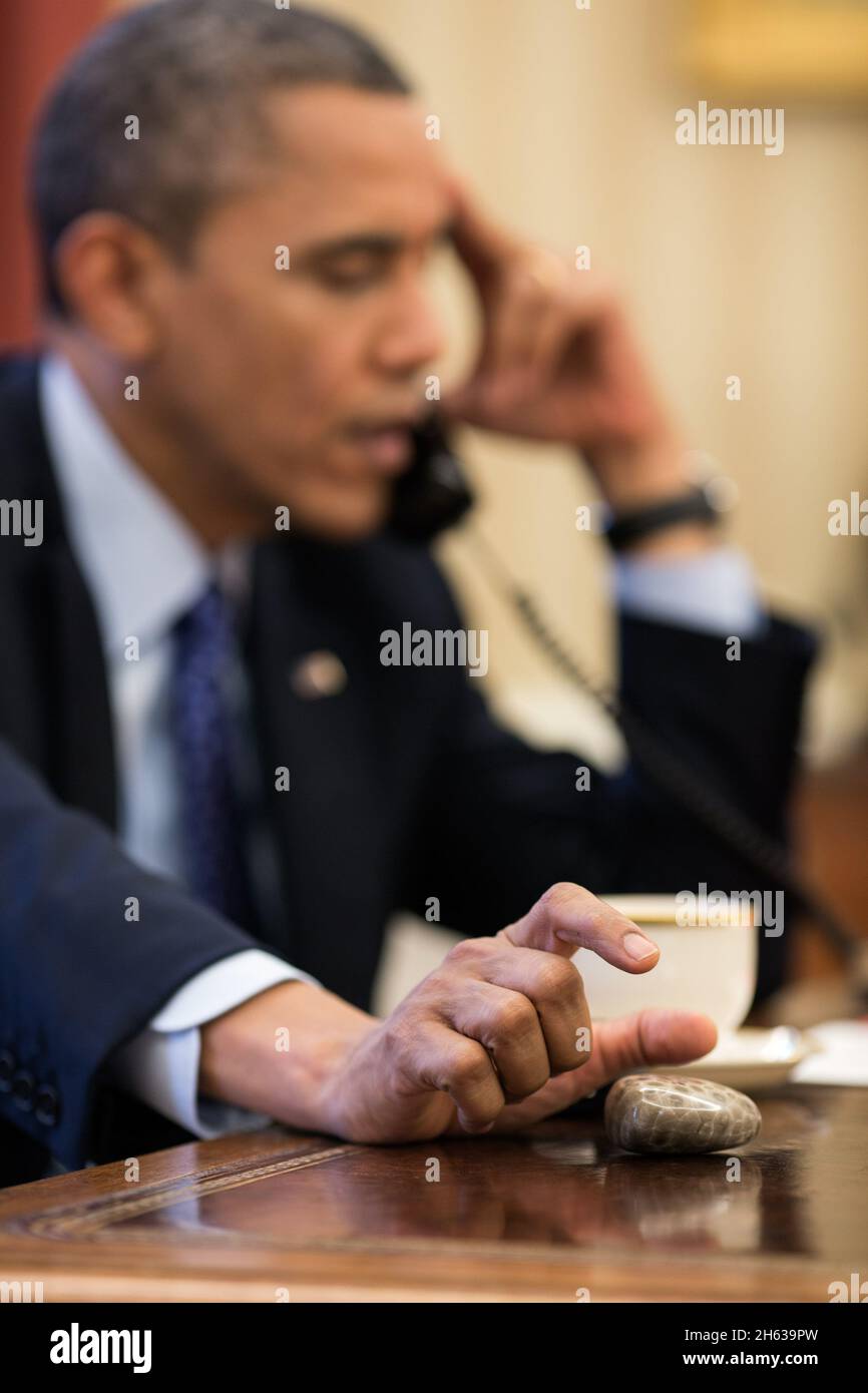 President Barack Obama plays with a Petoskey stone as he talks on the phone in the Oval Office, Dec. 6, 2012. Stock Photo