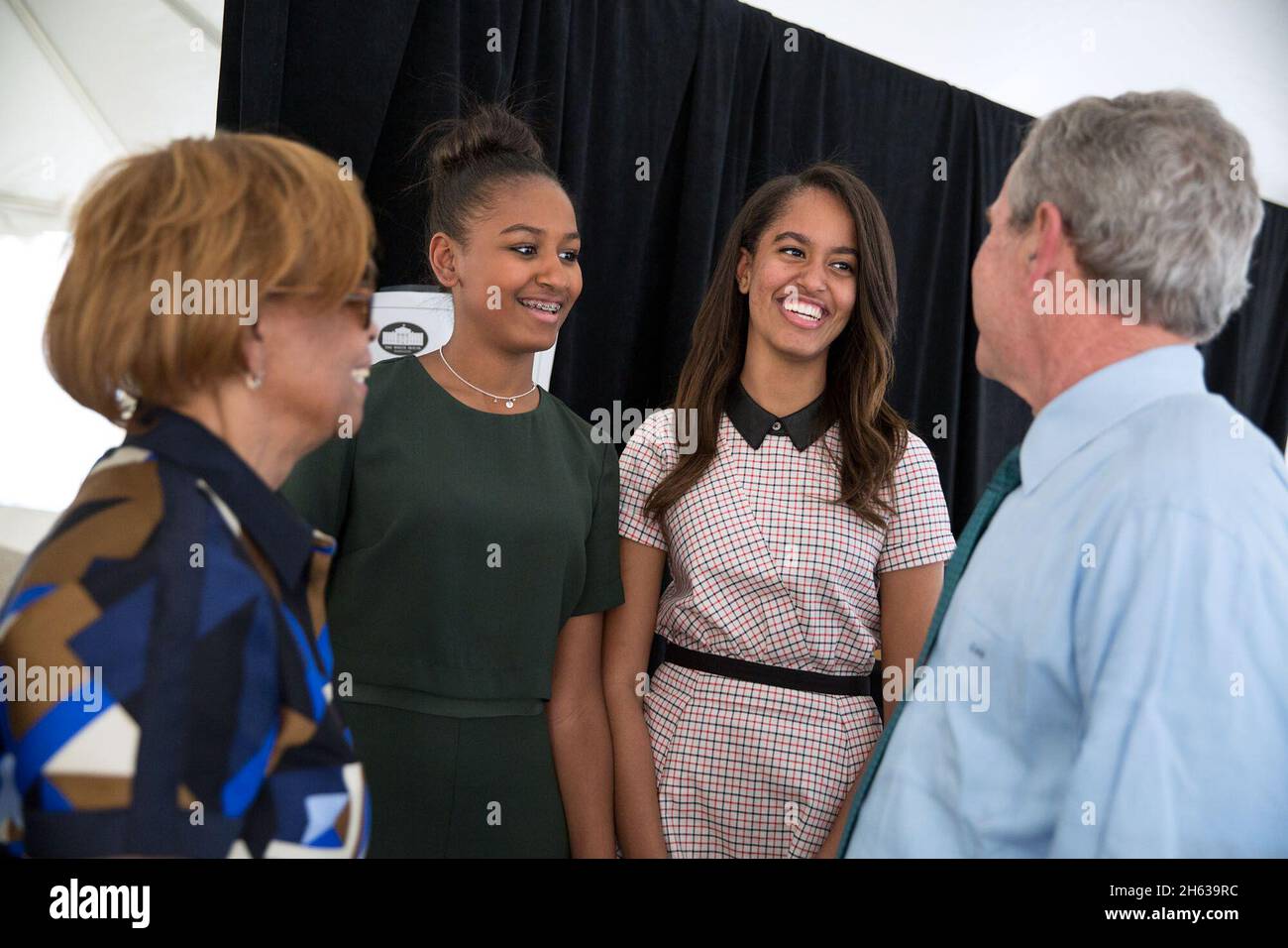 Backstage, former President Bush talks with Sasha and Malia Obama and Marian Robinson ca. 2015 Stock Photo