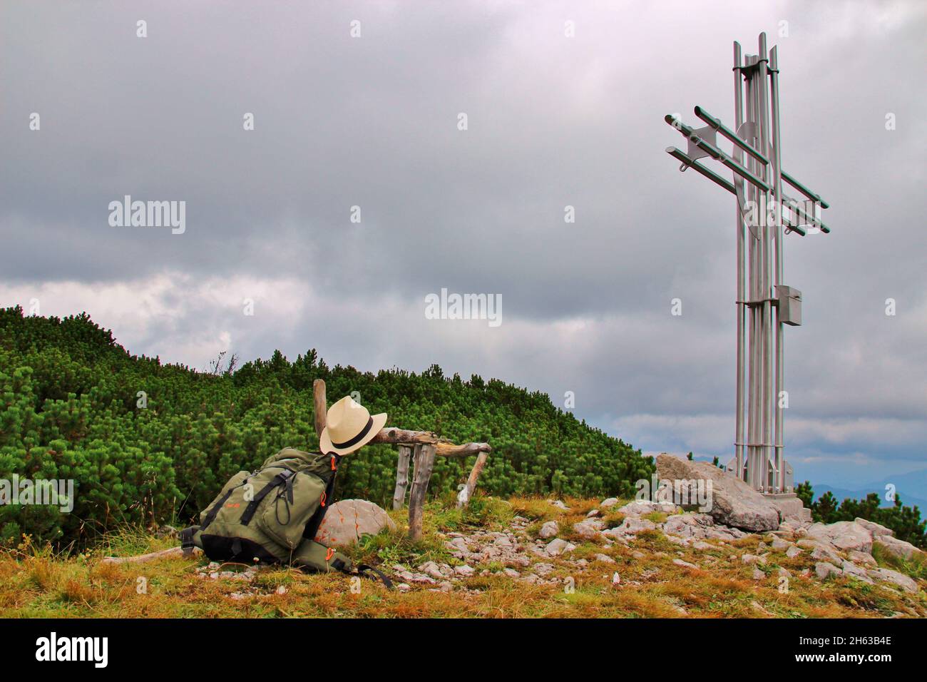 hike to latschberg,(1949) rucksack with a hiking hat in front of the summit cross,rofan mountains,brandenberger alps,tyrol,münster municipality Stock Photo