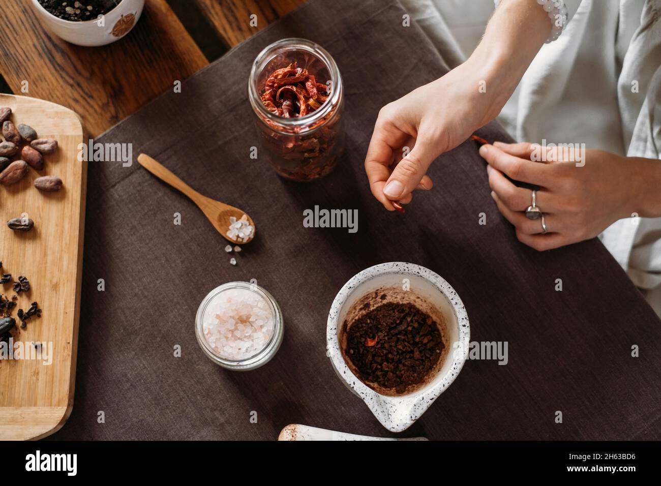 Woman hands putting chili pepper, solt in organic cacao, cooking on