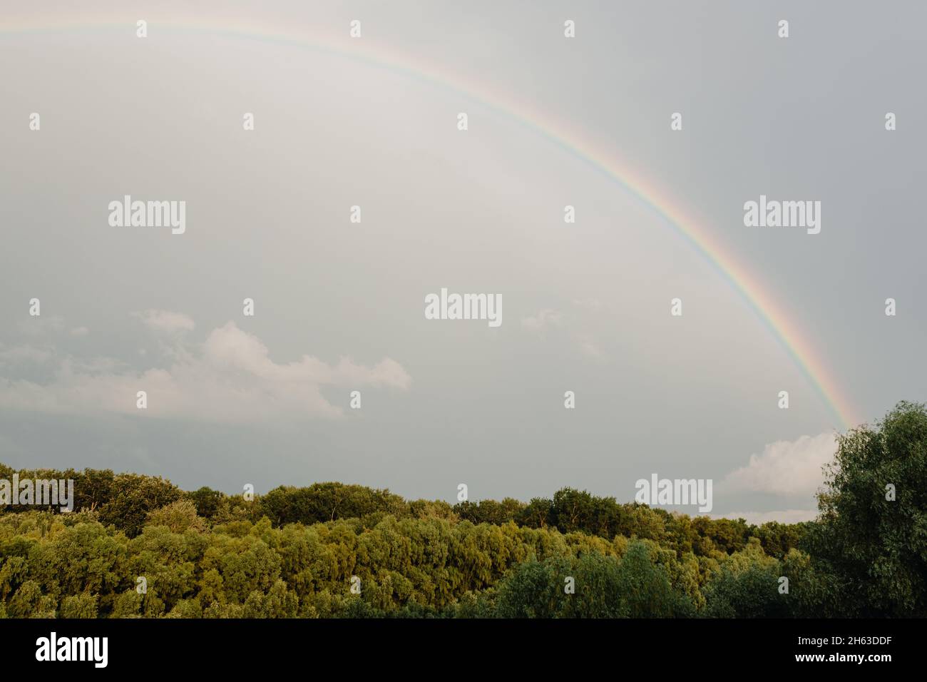 Rainbow after rain on cloudy sky Stock Photo - Alamy