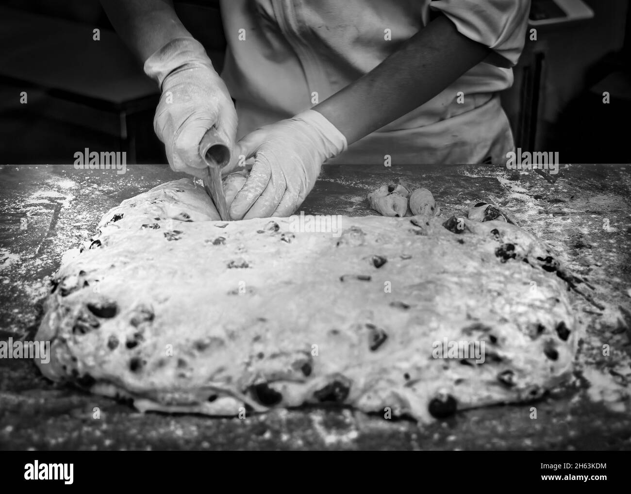 A baker cuts and dough on a table for chocolate chip cookies at a bakery in Hiroshima, Japan. Stock Photo