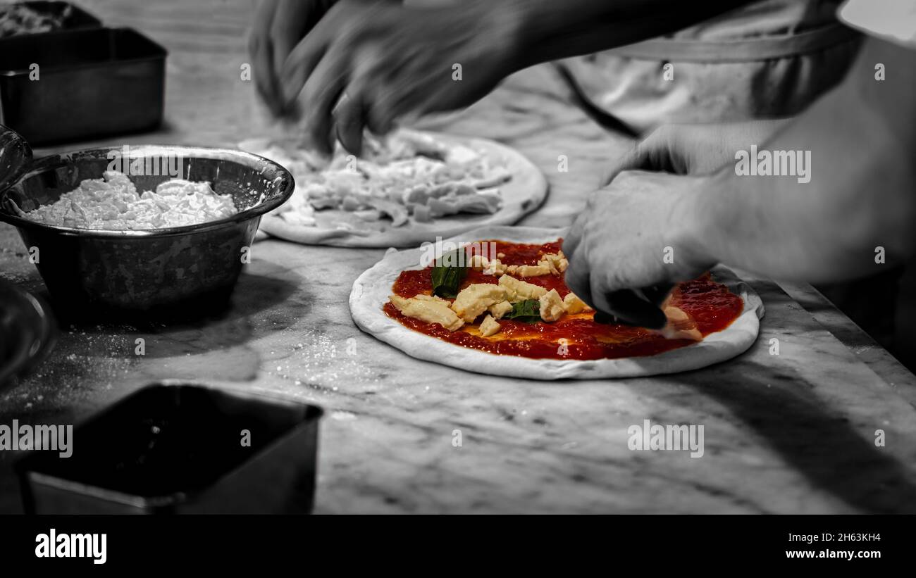 Pizzas, in selective color, being prepared by two chefs at a pizzeria in Kamakura, Japan Stock Photo