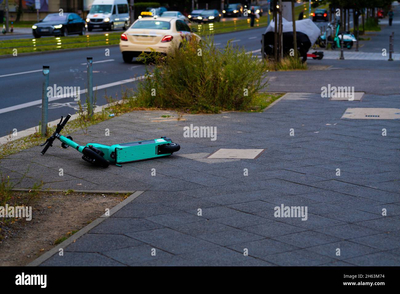 germany,berlin,august 17,2021,carelessly thrown down and overturned e-scooter on a sidewalk in the early morning in berlin,unsightly sight in berlin's city center,big problem in berlin Stock Photo