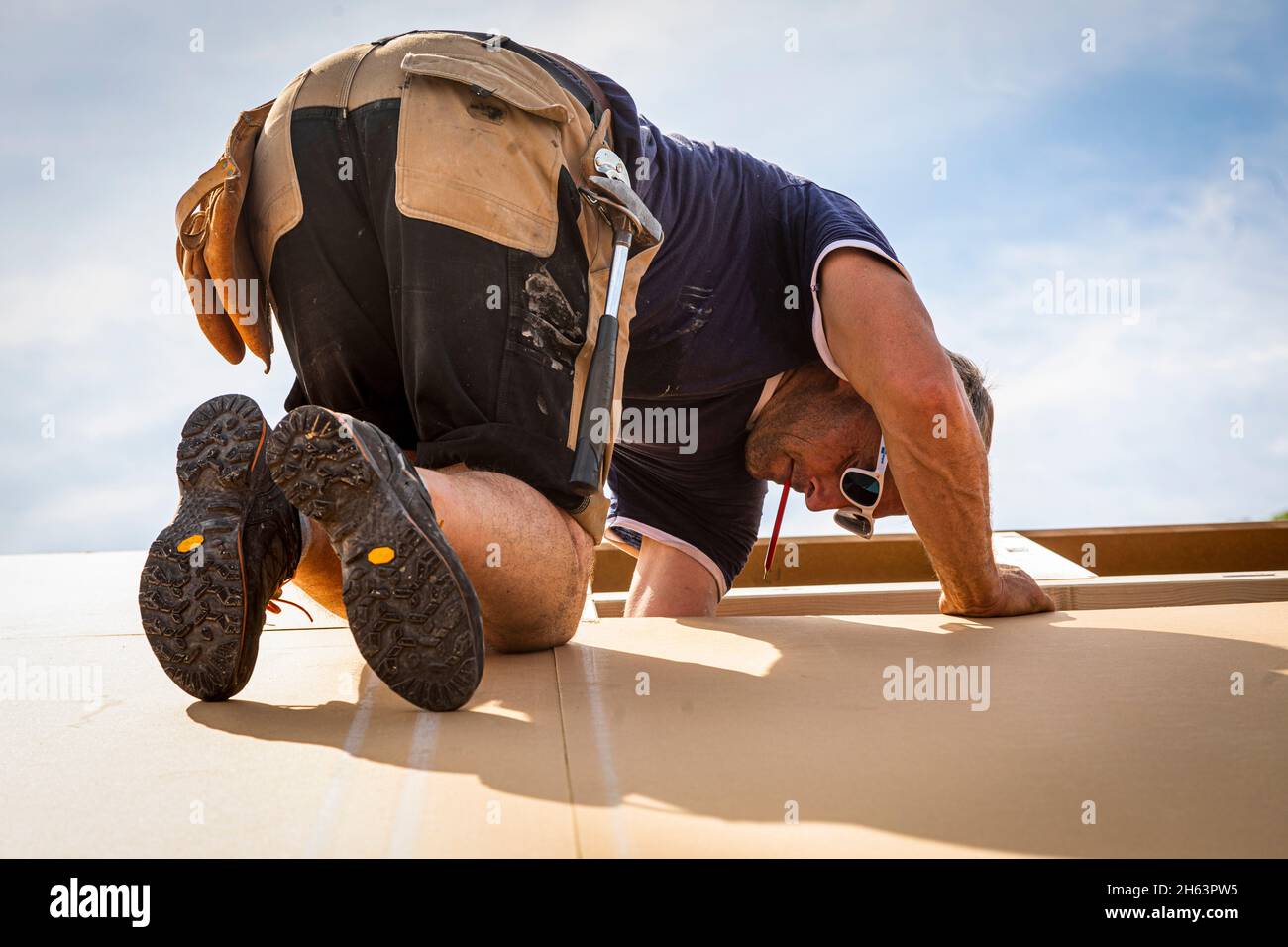 germany,bavaria,construction of a prefabricated wooden house,carpenter when roofing with chipboard, Stock Photo