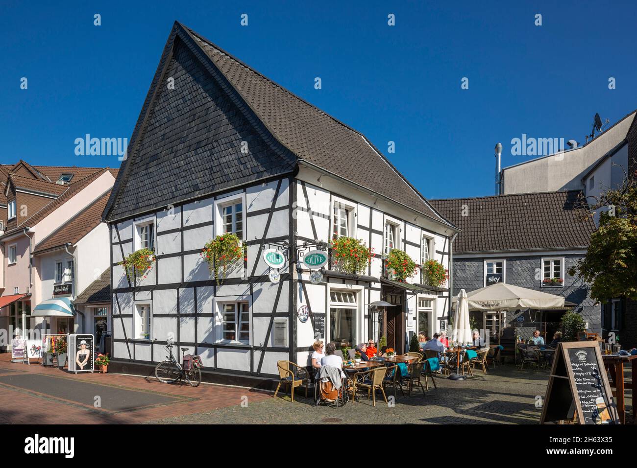 germany,hilden,bergisches land,niederbergisches land,niederberg,rhineland,north rhine-westphalia,nrw,half-timbered house markt 6,restaurant,people sitting at tables in the street cafe Stock Photo