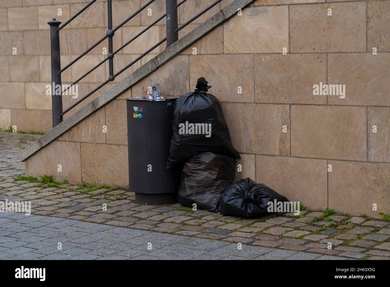 illegally disposed garbage bags next to a public trash can in berlin Stock Photo