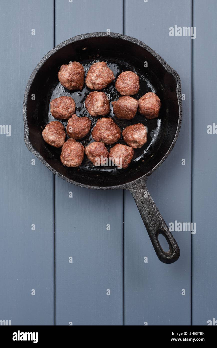 Beef meatballs prepared in cast iron pan on gray background copyspace