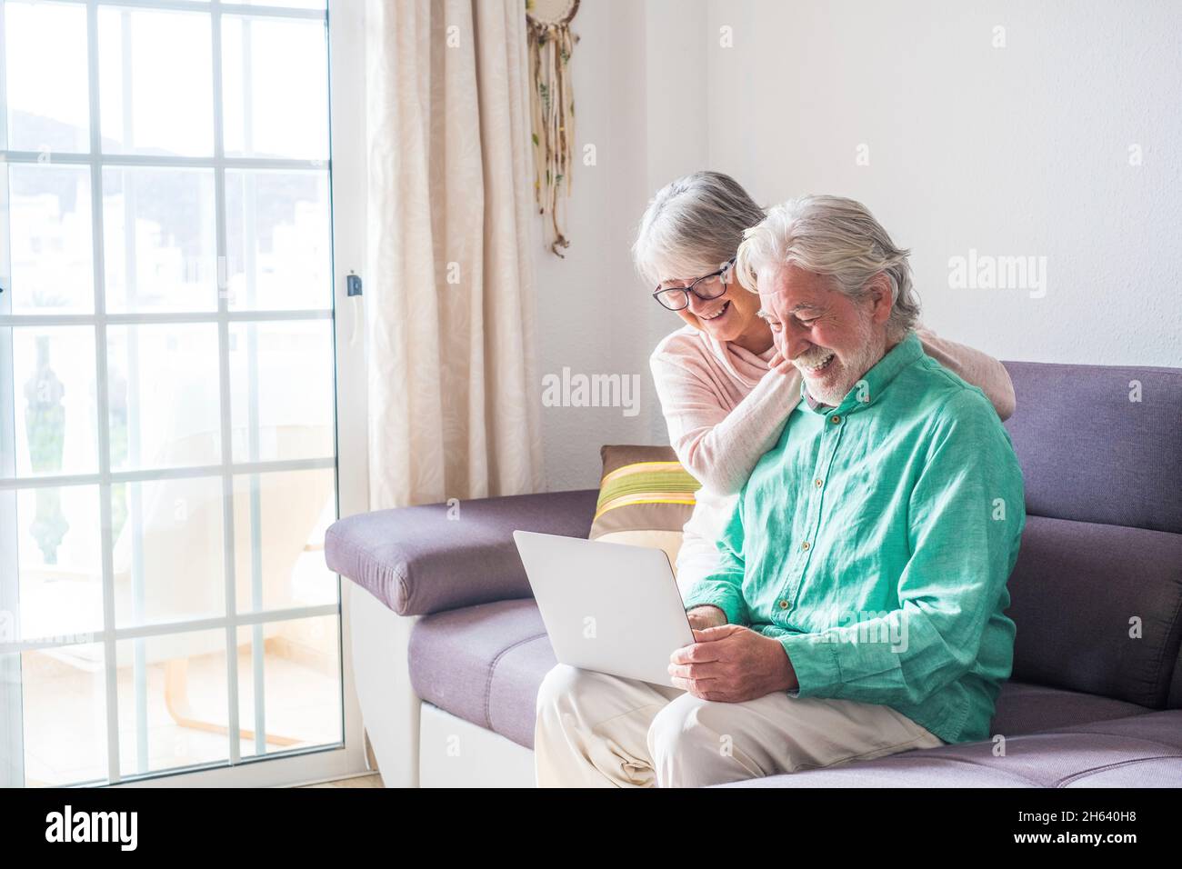 couple of two old and mature people at home using tablet together in sofa. senior use laptop having fun and enjoying looking at it. leisure and free time concept Stock Photo
