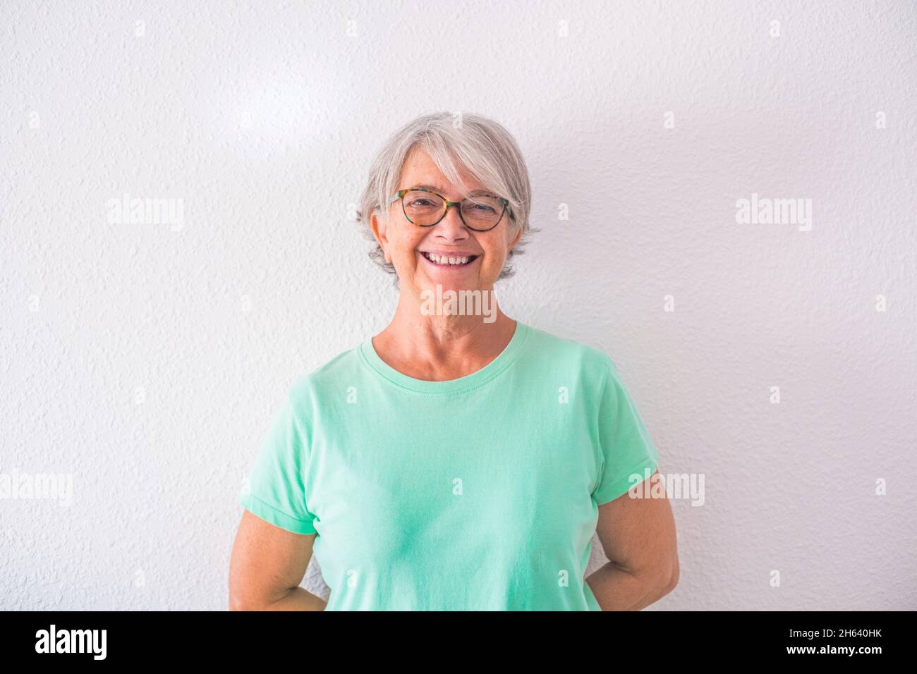 portrait of one pretty old and mature woman looking at the camera smiling and laughing - happy senior lady with a white background Stock Photo
