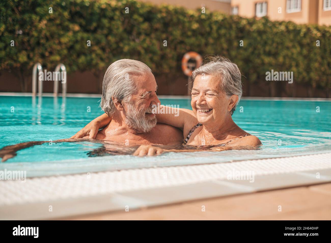 couple of two happy seniors having fun and enjoying together in the swimming pool smiling and playing. happy people enjoying summer outdoor in the water Stock Photo