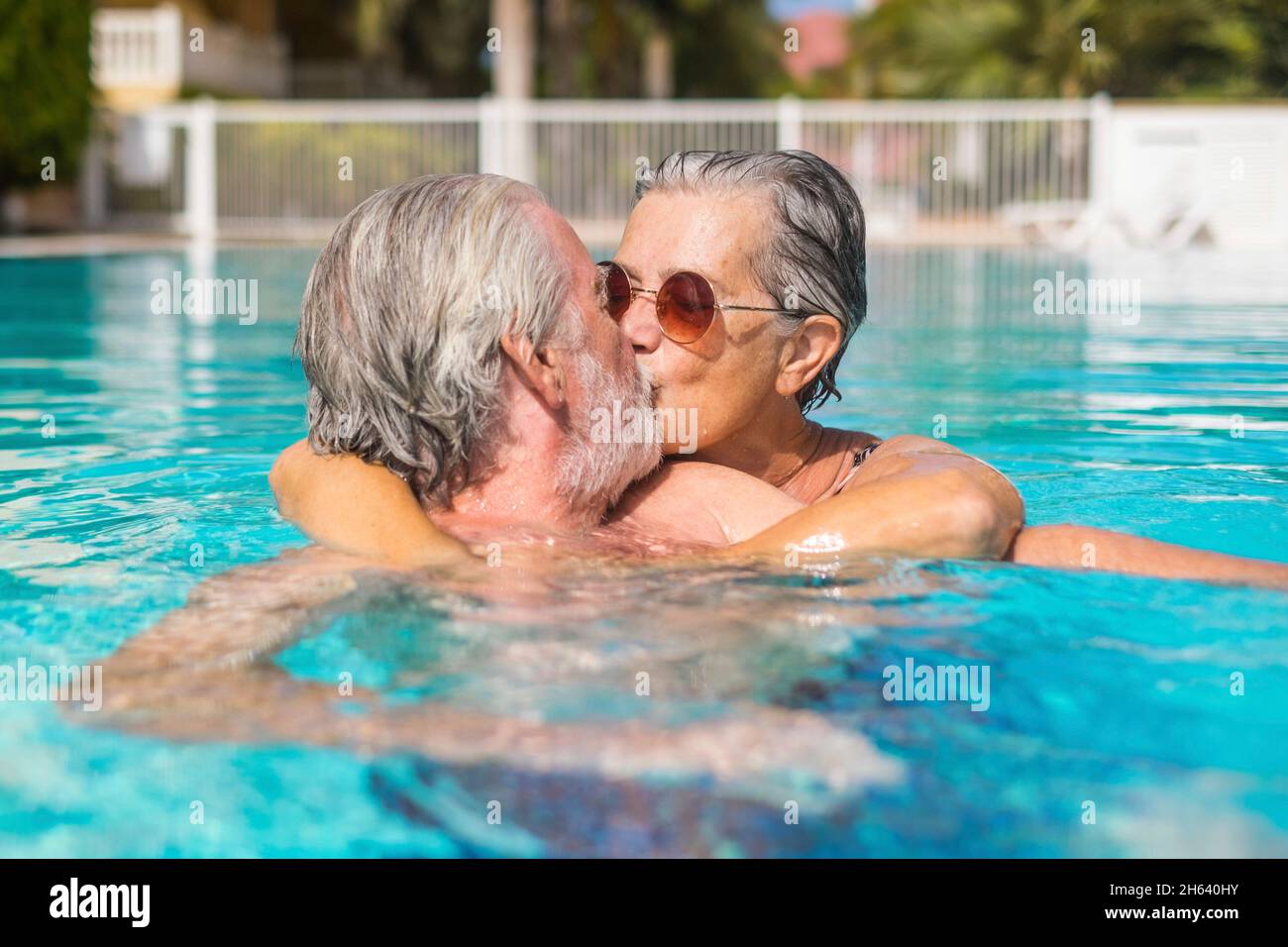 couple of two happy seniors having fun and enjoying together in the swimming pool smiling and playing. happy people enjoying summer outdoor in the water Stock Photo