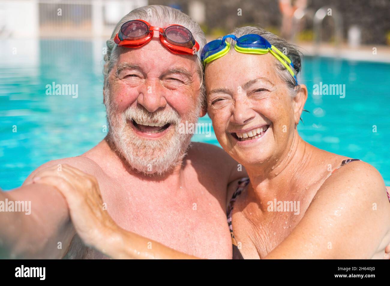 couple of two happy seniors having fun and enjoying together in the swimming pool taking a selfie picture smiling and looking at the camera. happy people enjoying summer outdoor in the water Stock Photo