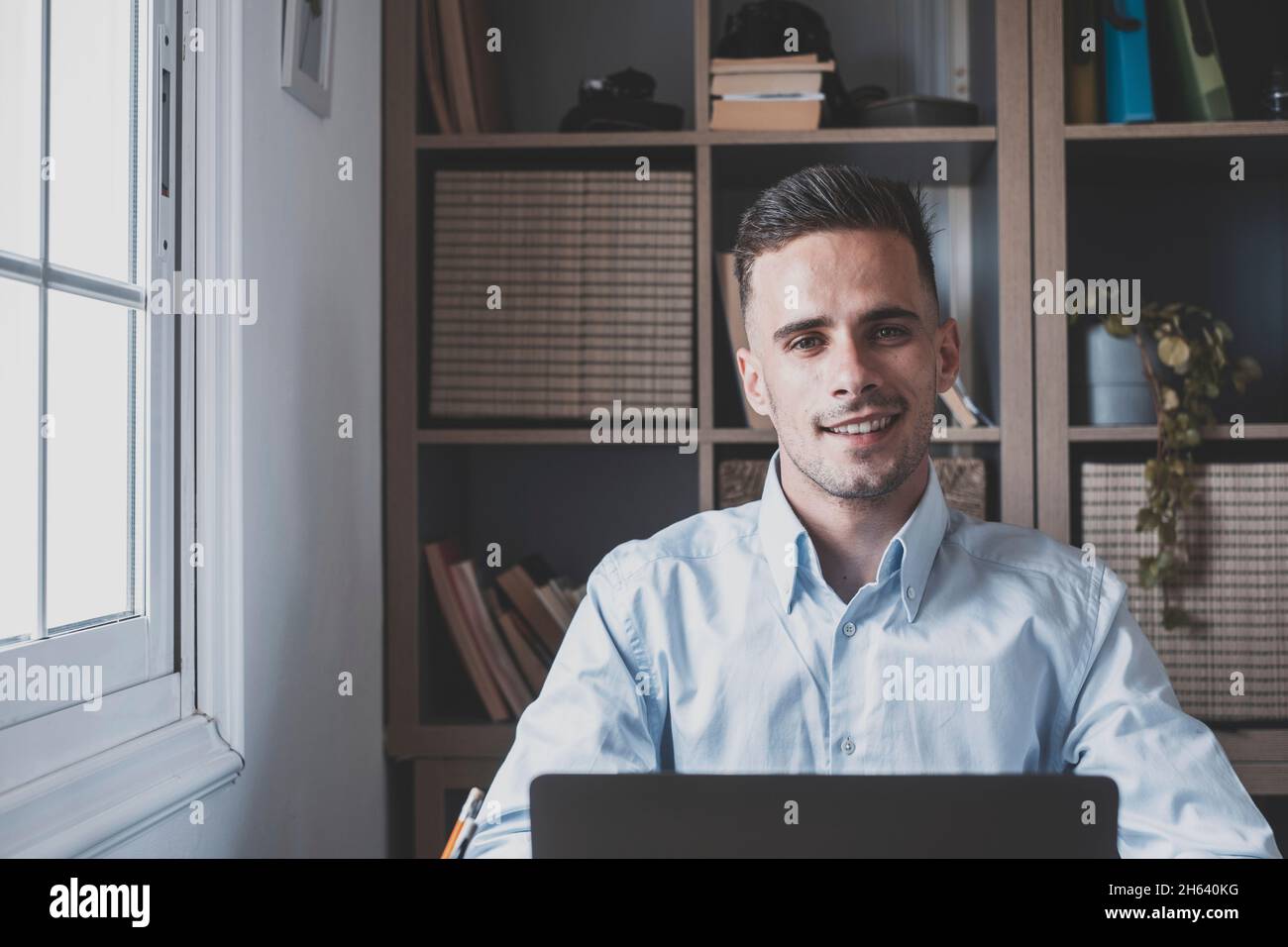 happy young man teenager smiling and talking in video conference studying and learning online with school. millennial doing homework at home calling Stock Photo