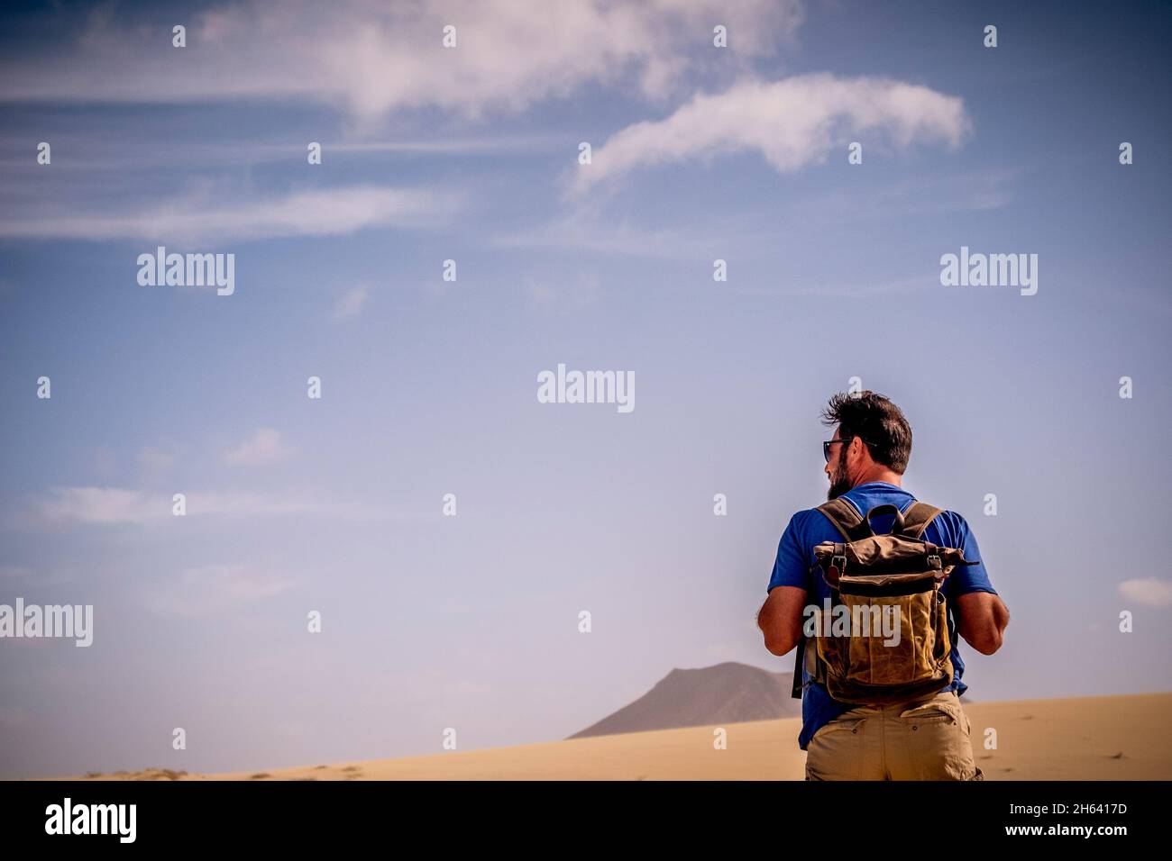 adventure lifestyle with explorer man with backpack viewed from back walking in the desert and mountains alone - wild people alternative travel vacation alone in outdoor wild nature Stock Photo