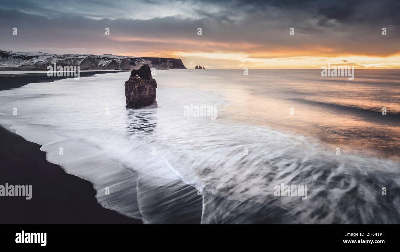 reynisfjall and reynisdrangar on the flooded beach in iceland at sunrise. Stock Photo