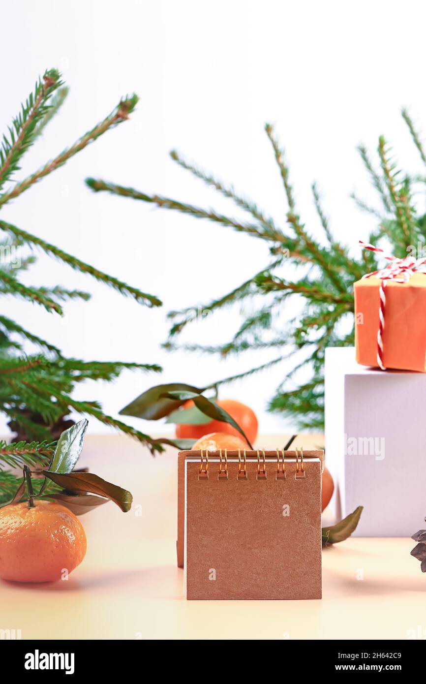 Christmas composition with spruce, tangerines, podium and notepad. Soft selective focus. Winter festive background. Stock Photo