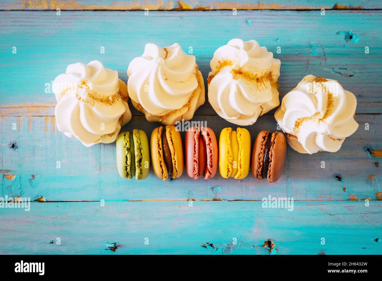 high angle view of fresh macaroons and cupcakes on wooden table. ready to eat bakery made dessert on table. top view of delicious freshly made bakery items on wooden table Stock Photo