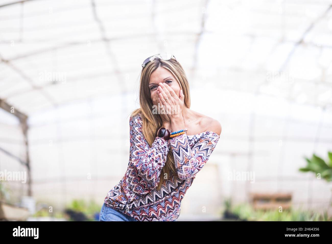 portrait of excited beautiful woman covering her mouth with hands trying to stop giggling. pretty stylish amazed young woman covering her mouth with both hands. cheerful woman covering her mouth Stock Photo