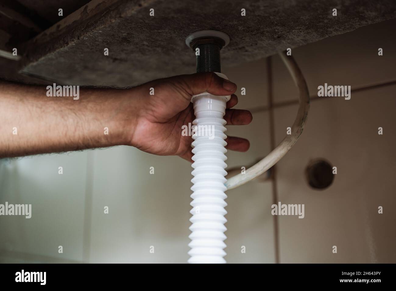 Plumber installs a siphon pipe on the kitchen sink. Refurbishment in the apartment. Elimination of leakage in the sink. Stock Photo