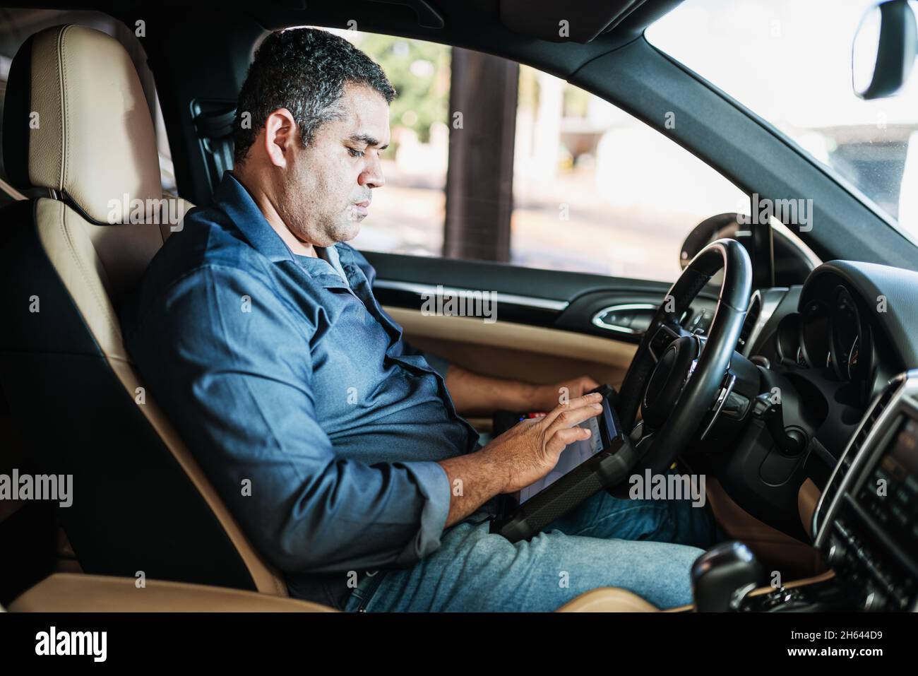 Car diagnostic. Technical inspection, car electronics. A Latin man holds a digitizing device