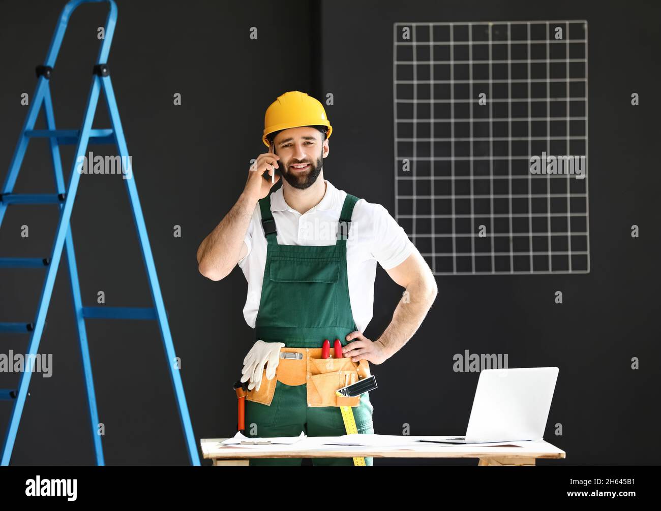Construction worker talking by mobile phone in room Stock Photo