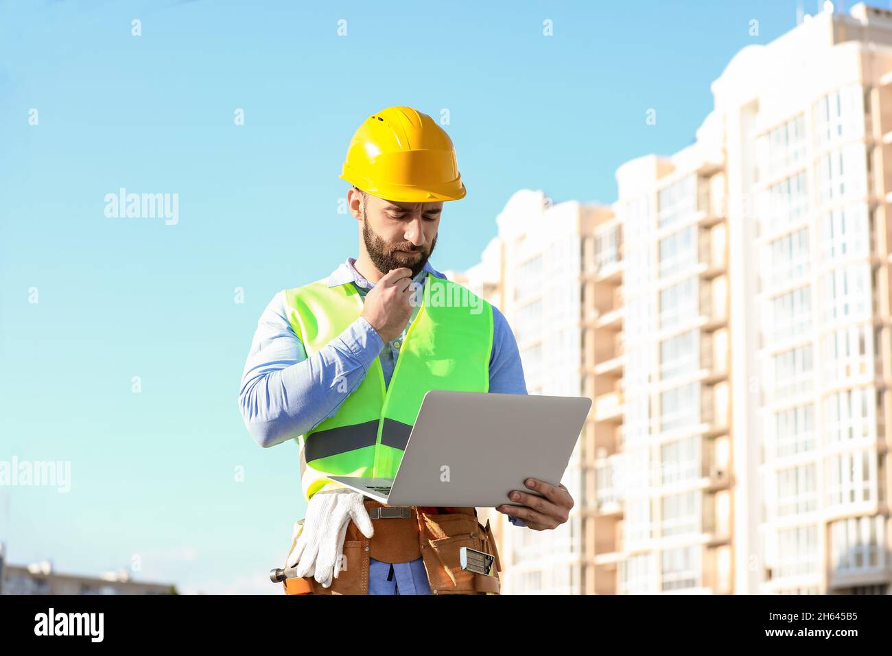 Thoughtful construction worker using laptop outdoors Stock Photo