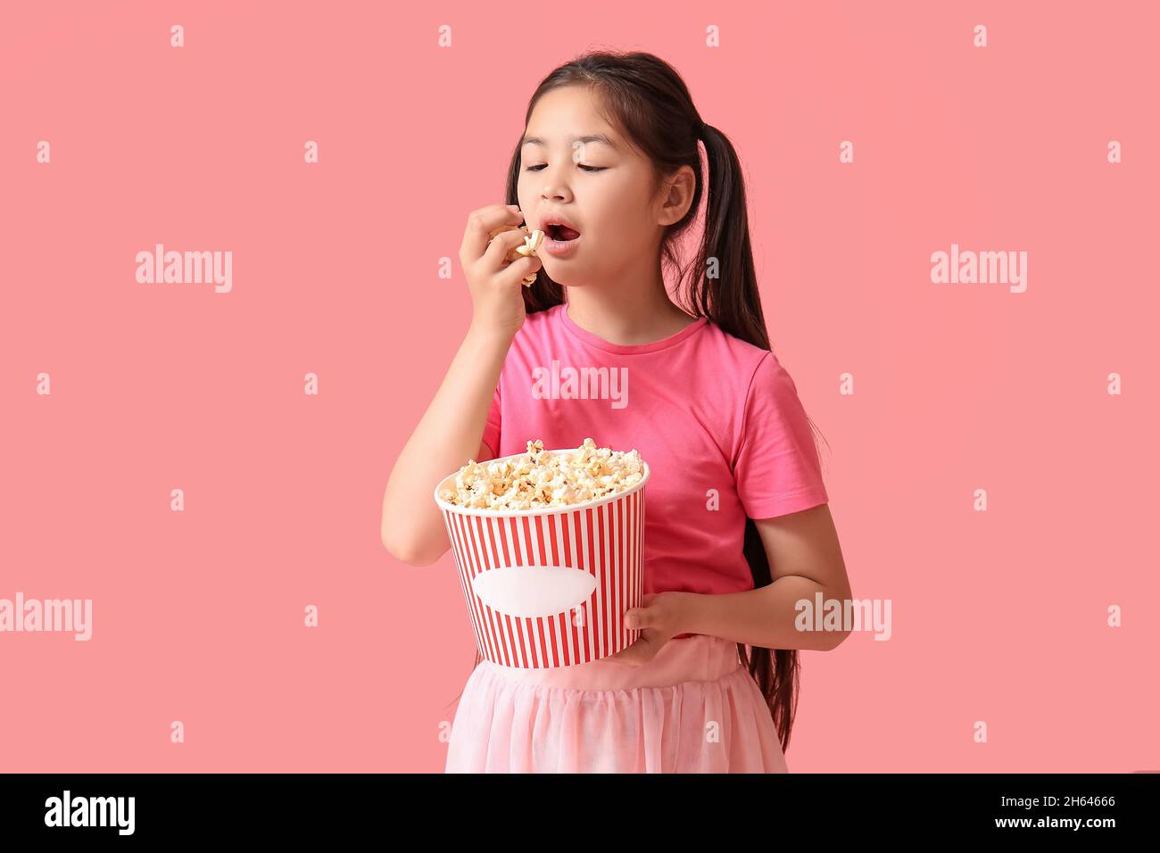Cute girl eating popcorn on pink background Stock Photo Alamy