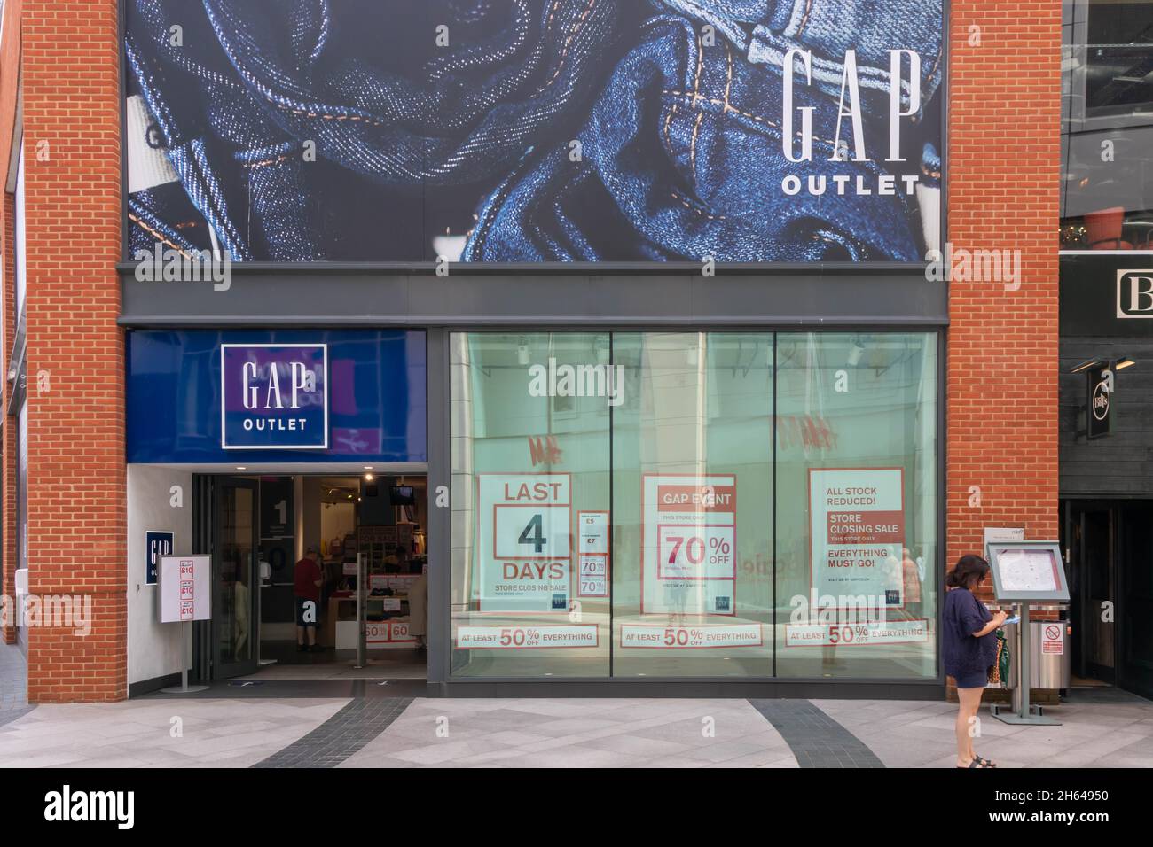 HIgh Wycombe, England - July 21st 2021: A woman checks her phone outside a GAP store. All Gap stores have closed.. Stock Photo