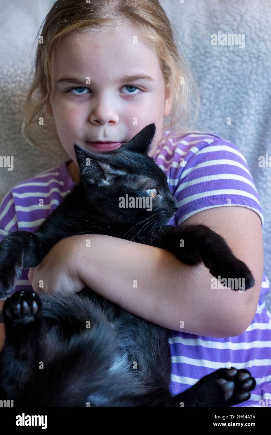 Four year old girl struggling to hold her two month old squirming kitten, Mr. Pickles (MR) (PR) Stock Photo