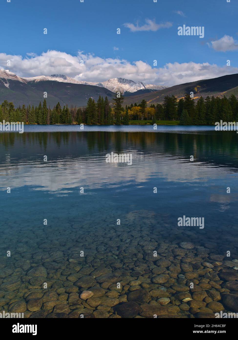 Stunning portrait view of beautiful Lake Beauvert in Jasper, Alberta, Canada in the Rocky Mountains with illuminated round stones on the shore. Stock Photo