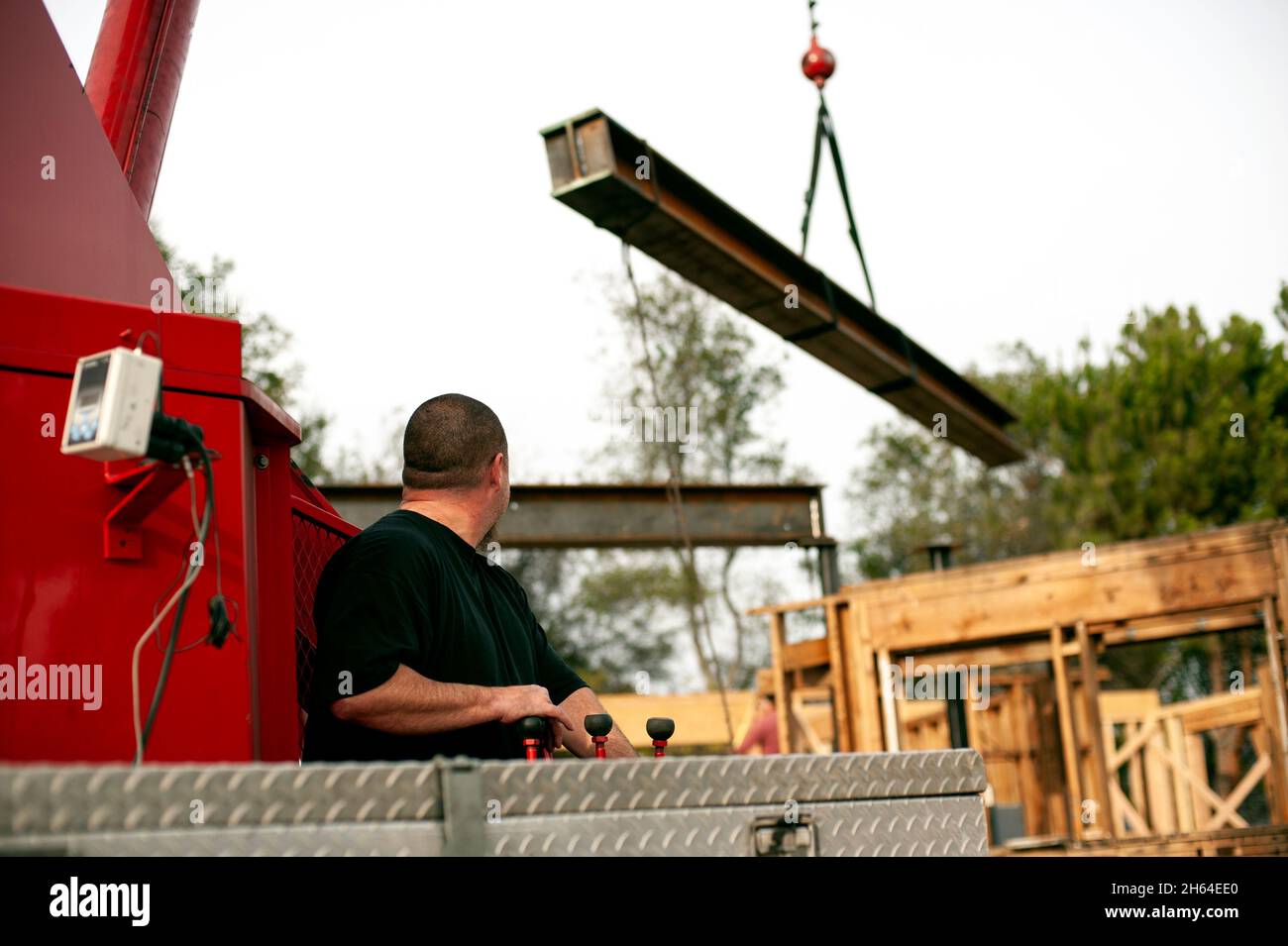Crane operator lifting a large steel I-beam into place on a construction project Stock Photo