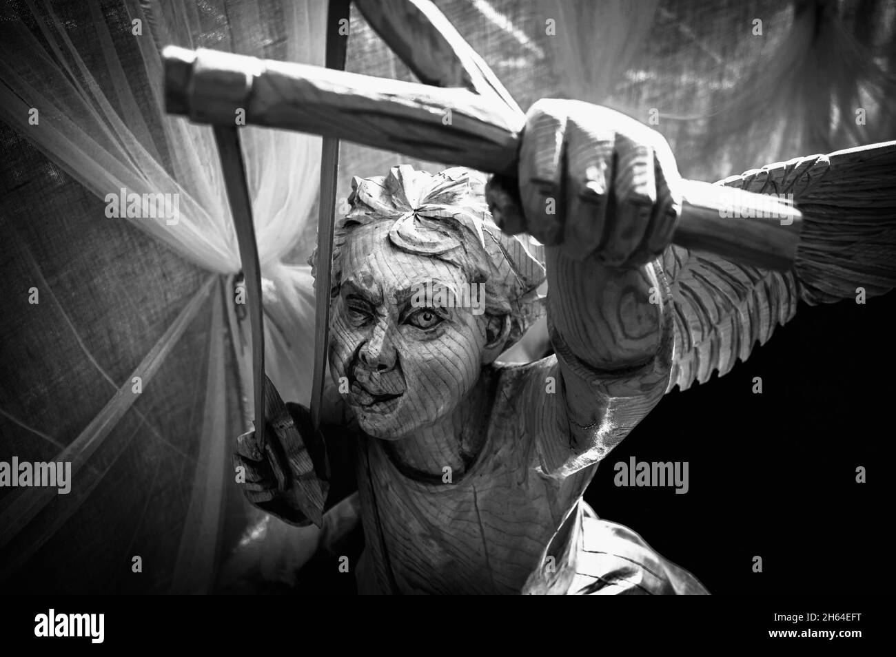 Wooden sculpture of an angel boy aiming a slingshot in Ruskeala Mountain Park. Karelia, Russia. Black and white. Stock Photo