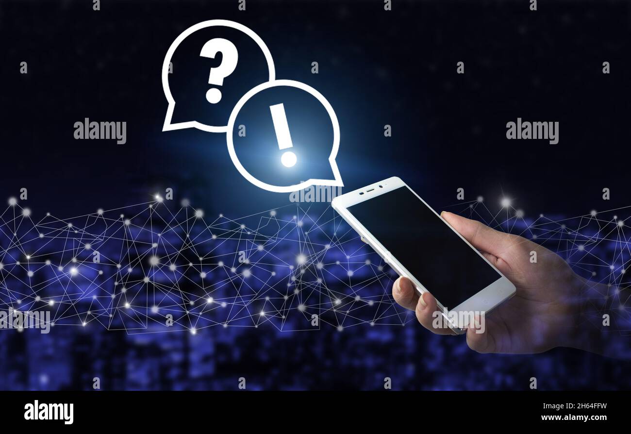 Business support concept. Problems and solutions. Hand hold white smartphone with digital hologram question mark sign on city dark blurred background. Stock Photo