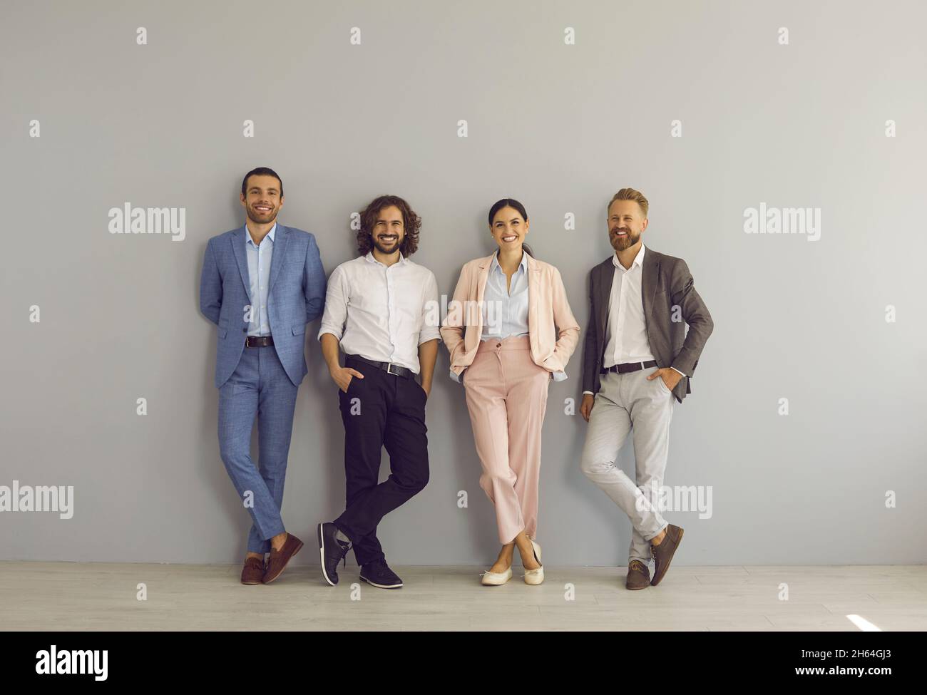 Group portrait of happy successful young business people standing by studio wall Stock Photo