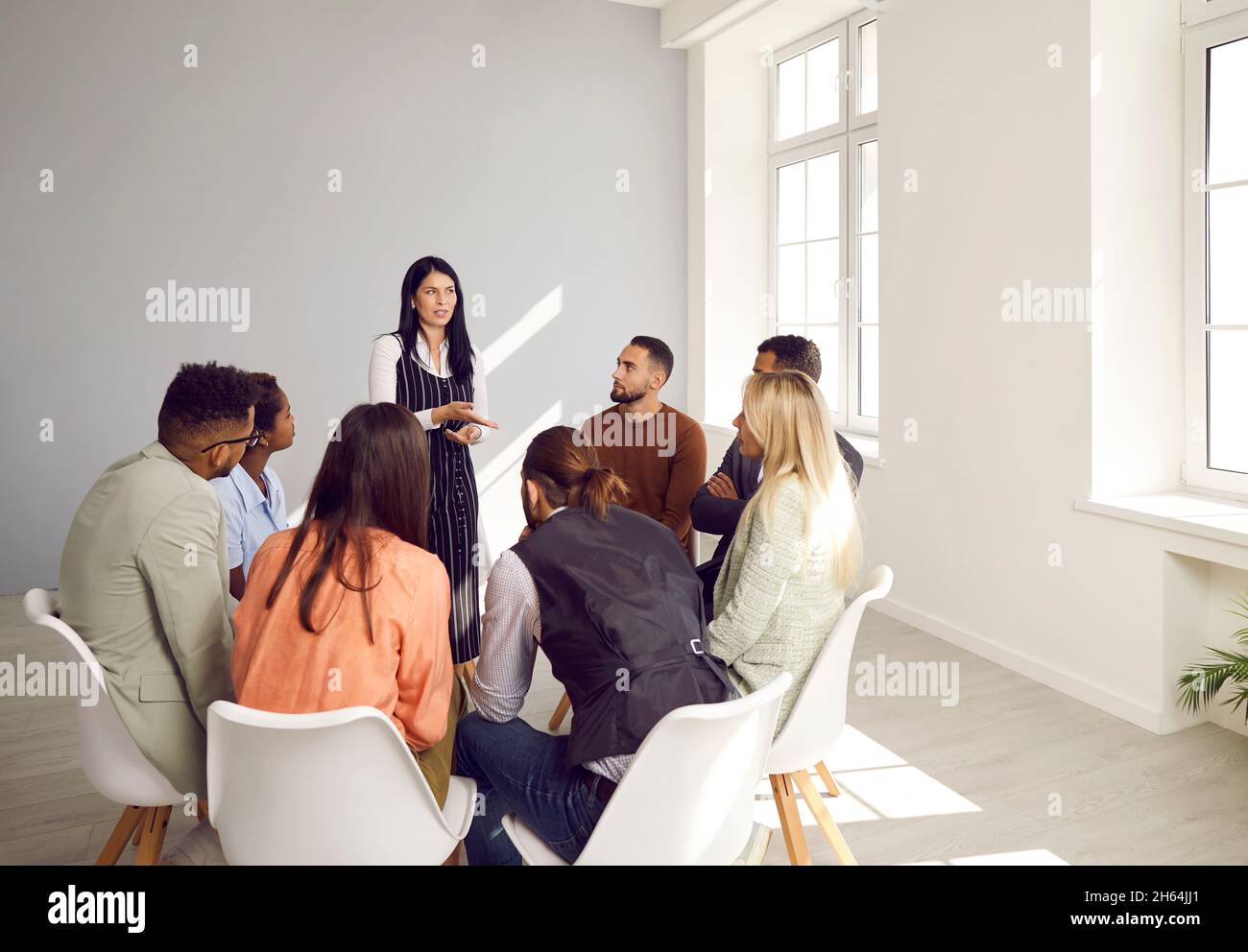 Woman speaks at group therapy or psychotherapy meeting providing psychological help to people. Stock Photo