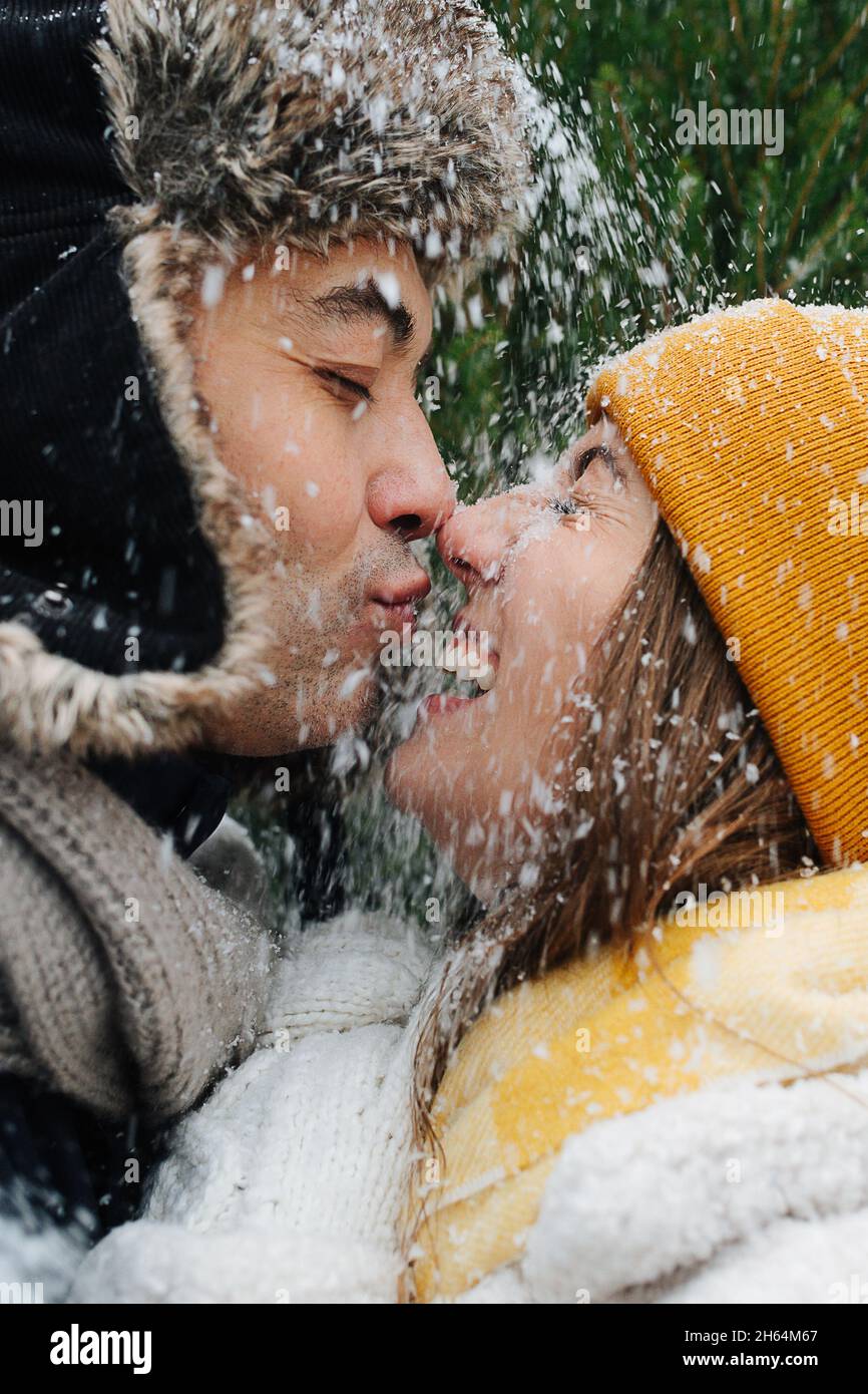 Emotional portrait, close-up faces, couple kissing snow is falling on them Stock Photo