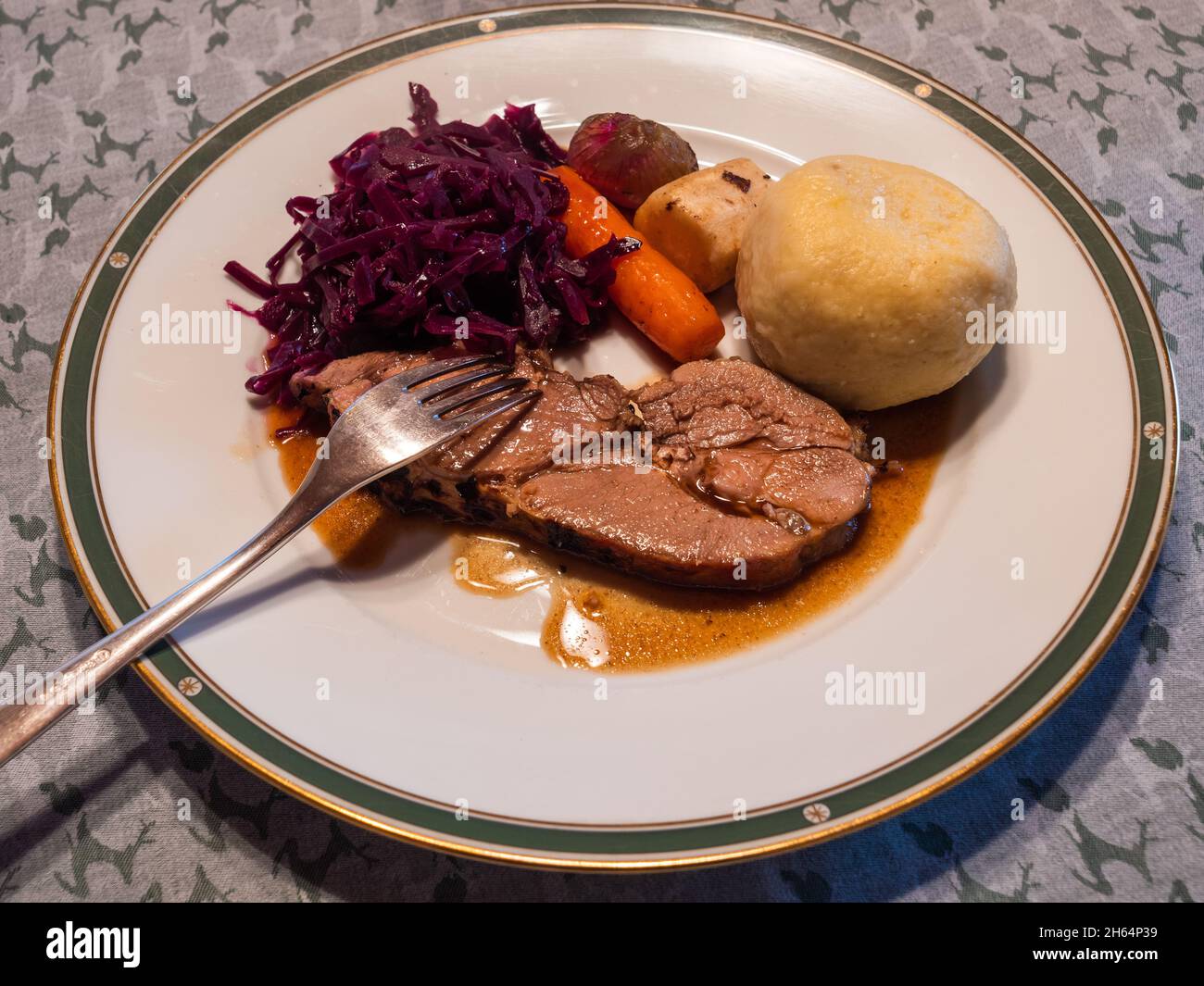 Slice of Roast Young Wild Boar Piglet with Red Cabbage, Potato Dumpling, Winter Vegetables and Gravy Stock Photo